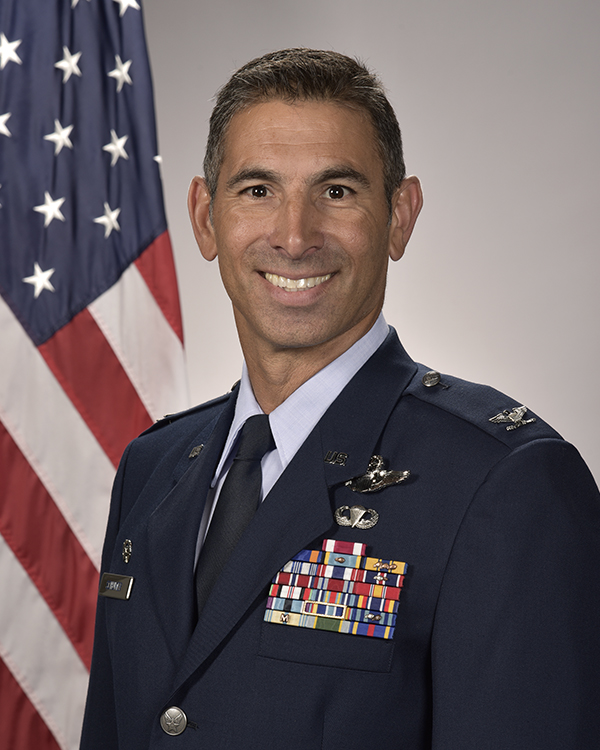 A portrait of a man in Air Force blue service dress with an American flag in the background.