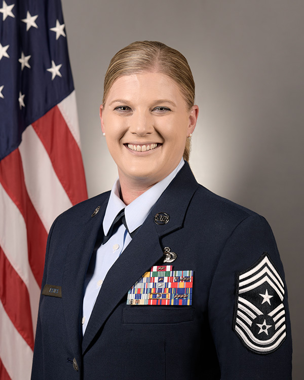Studio photo of Chief Master Sgt. Andrea Estes in service dress with the American flag in the background.